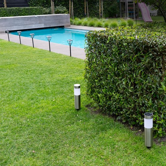 RVS solar tuinlampen langs een zwembad en gazon. De lampen hebben een witte lichtkap.