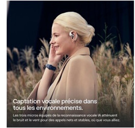 Vrouw met blonde paardenstaart draagt witte Shokz oordopjes, luisterend naar muziek in een veld.