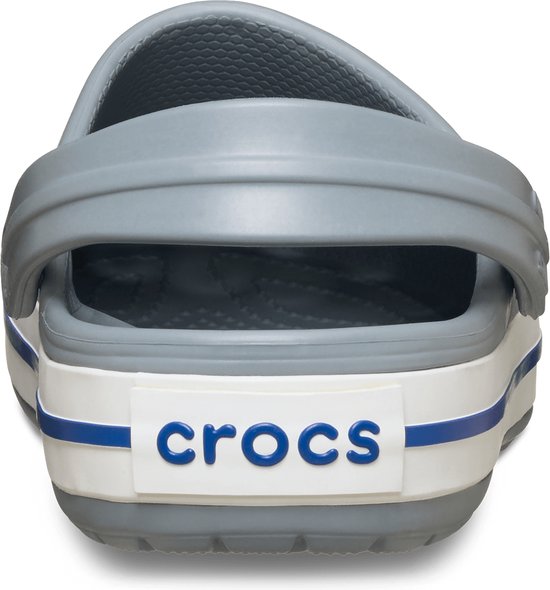 Achterkant van een grijze Croc met witte en blauwe strepen op de zool.
