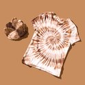 Jonge man met zonnebril, leunt tegen een gele bakstenen muur, draagt een bruin-witte tie-dye t-shirt.