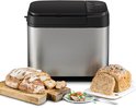 Zilverkleurige broodbakmachine met gesneden brood en een heel brood met zaden erop.