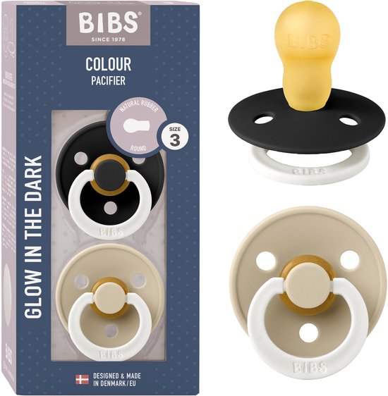 Lot de 2 tétines BIBS Colour Glow. Tétine noire avec anneau blanc, tétine beige avec anneau blanc et détail doré. Brille dans le noir.