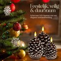 Drie realistische wax LED-kaarsen in dennenappelvorm met witte accenten, naast een kerstboom.