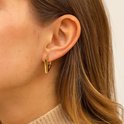 Goudkleurige vierkante oorringen, gedragen door een model.