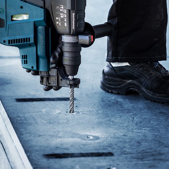Man met handschoenen boort in betonnen trede met een Bosch boorhamer en SDS plus-7X boor.