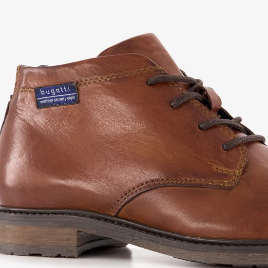 Detail van een cognac leren Bugatti veterschoen met veters en blauw label 'nineteen seventy eight'.