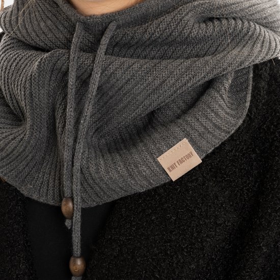 Close-up van een grijze gebreide colsjaal met capuchon, met een leren label 'RMIT FACTORY'.