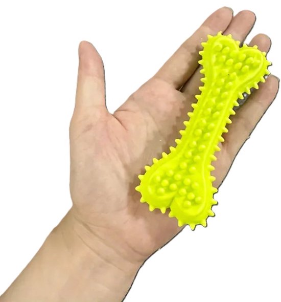 Hand die een geel botvormig kauwspeeltje vasthoudt, met nopjes en stekels.