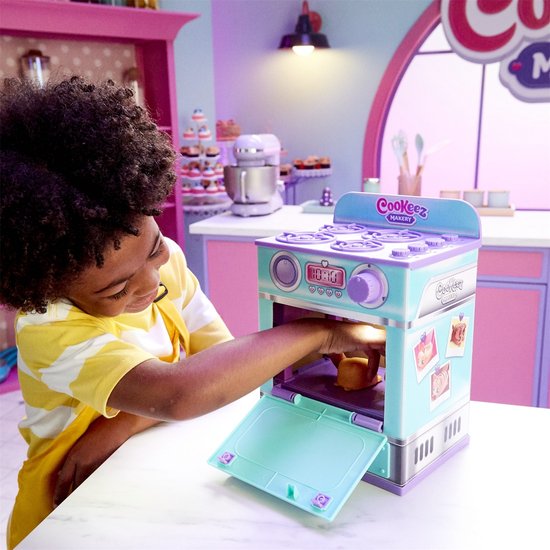 Jongen met gele gestreepte shirt doet een bruine pluche donut in een turquoise en paarse oven.