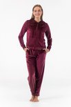 Model draagt een bordeauxrode velours loungewear set. De set bestaat uit een hoodie met rits en zakken, en een joggingbroek.