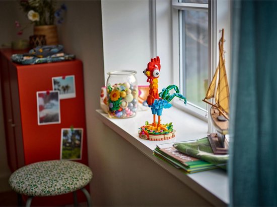 Figurine LEGO Heihei avec une tête rouge, un corps jaune-orange, des ailes bleues et une queue verte, sur une base ronde.