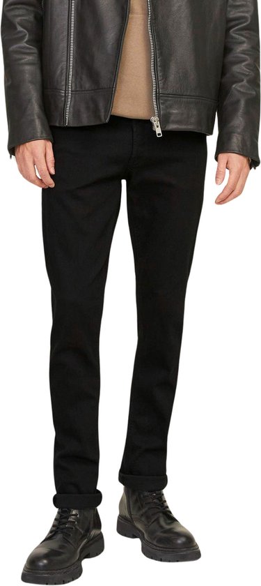 Onderlichaam van een man in zwarte skinny jeans, beige hoodie en zwart leren bikerjack.