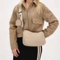 Model met taupekleurige schoudertas van Charm London en bijpassend etui, gedragen met bruine jas en gestreepte rok.