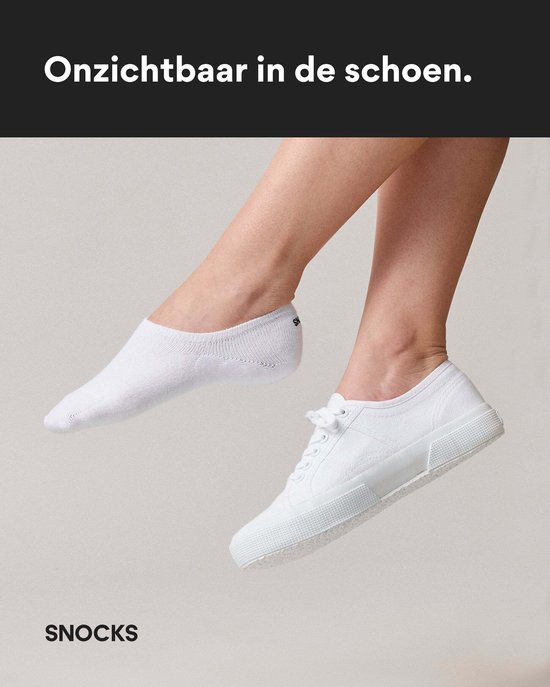 Voeten van een vrouw die witte lage sneakers draagt met witte enkelsokken die nauwelijks zichtbaar zijn.