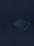 Close-up van het geborduurde vierkante donkerblauwe logo op een donkerblauwe sweater.