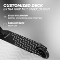 Zwarte stuntstep met een wit zigzagpatroon op het deck. "CUSTOMIZED DECK EXTRA GRIP MET UNIEK DESIGN".