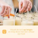 Handen knippen een kaarsenlont op de juiste lengte met een schaar.
