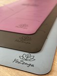 Gestapelde yogamatten in roze, grijs en lichtblauw met lotusbloem-logo.