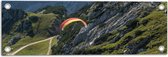 WallClassics - Tuinposter – Paraglidend door de Bergen en Natuur - 60x20 cm Foto op Tuinposter  (wanddecoratie voor buiten en binnen)