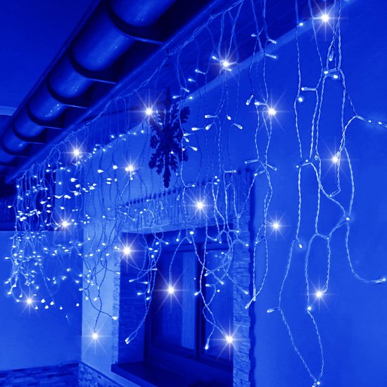 Blauwe LED-ijspegelverlichting hangt aan de dakrand boven een raam, sfeervolle blauwe gloed op de muur.