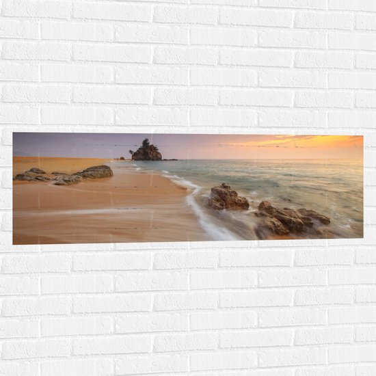 WallClassics - Muursticker - Zee met Rotsen bij Pastelkleurige Lucht - 120x40 cm Foto op Muursticker