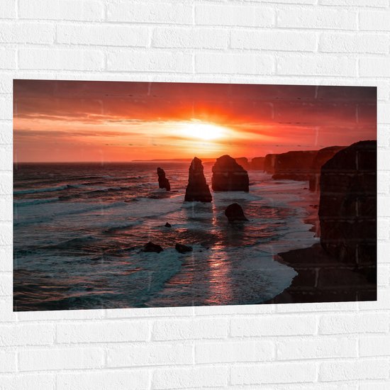 WallClassics - Muursticker - Rotsen in de Zee met Zonsondergang - 105x70 cm Foto op Muursticker