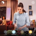 Vrouw snijdt groente in keuken met Philips Hue verlichting.