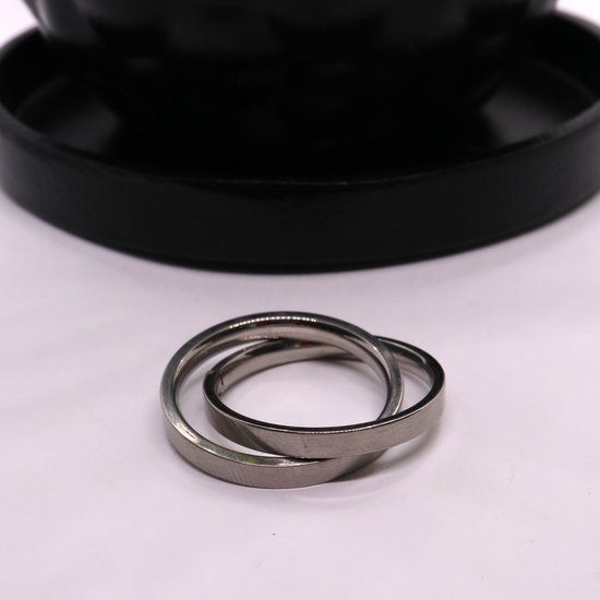 Twee zilverkleurige ringen in elkaar op een witte ondergrond.