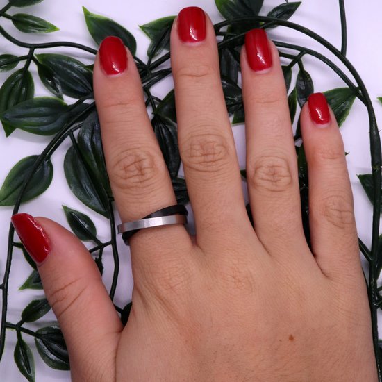 Hand met rode nagellak en een zilverkleurige en zwart matte ring om de middelvinger.