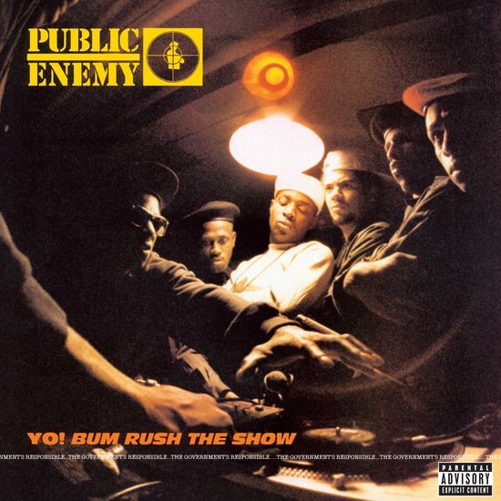 Albumhoes van Public Enemy's 'Yo! Bum Rush The Show'. Een groep mannen staat rond een draaitafel, verlicht door een lamp.