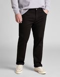 Man in een grijze sweater en zwarte jeans, met opgerolde broekspijpen. Draagt crèmekleurige sneakers.