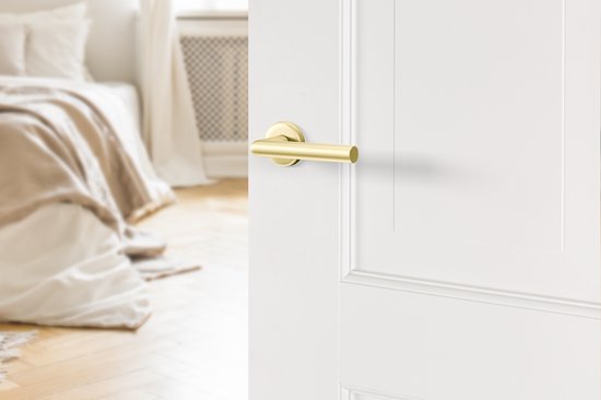 Gouden AXA deurklink met ronde rozet op een witte deur, slaapkamer op achtergrond.
