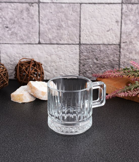 Een leeg, doorzichtig glazen theeglas met een gedessineerde bodem en een handvat.