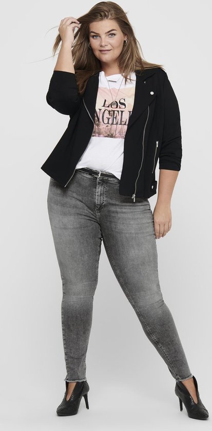 Model met bruin haar in een zwarte jas, T-shirt met tekst en grijze skinny jeans.