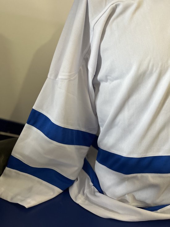 Detailopname van een wit ijshockey shirt met blauwe strepen op de mouwen.