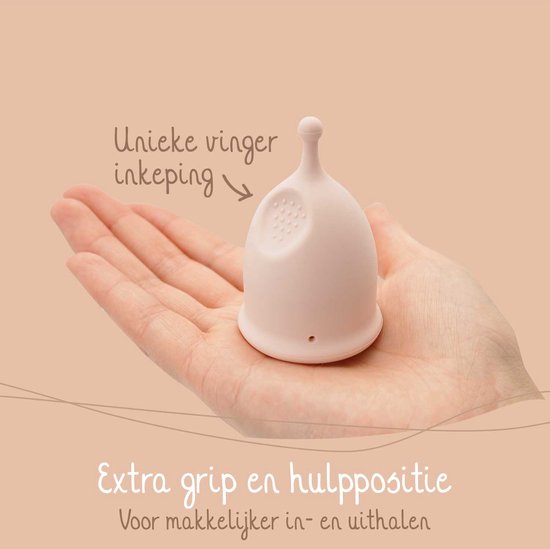 Coupe menstruelle rose pâle avec encoche et prise supplémentaire, dans une paume. 'Encoche de doigt unique', 'Prise et position d'aide supplémentaires'.