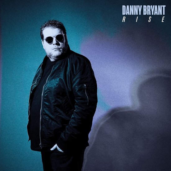 Danny Bryant staat op een blauw-paarse achtergrond en draagt een zwarte bomberjack en zonnebril. Titel: "DANNY BRYANT RISE".