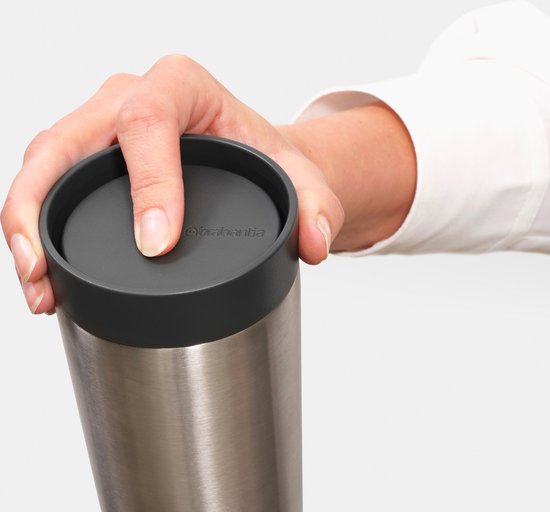Hand sluit het grijze deksel van een roestvrijstalen thermosbeker.