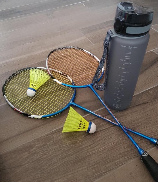 Matgrijze King Mungo drinkfles van 1 liter naast twee badmintonrackets en twee shuttlecocks op een houten vloer.
