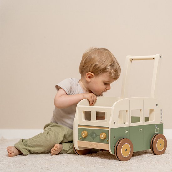 Groene en beige houten loopwagen met twee ronde wielen. Een jongetje zit ernaast.