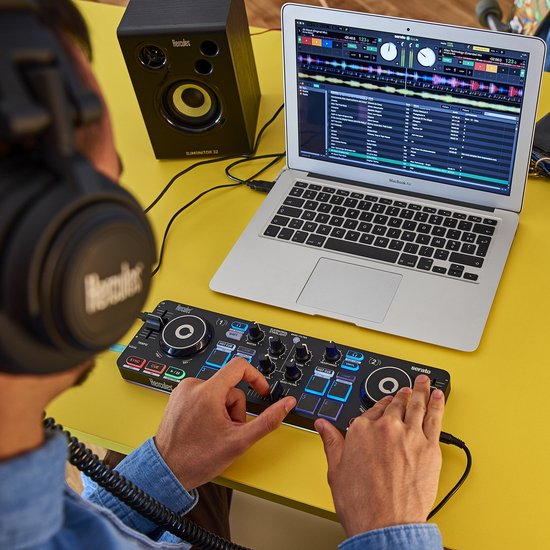 Zwarte DJ-koptelefoon, gedragen door een man die een DJ-controller en laptop gebruikt.