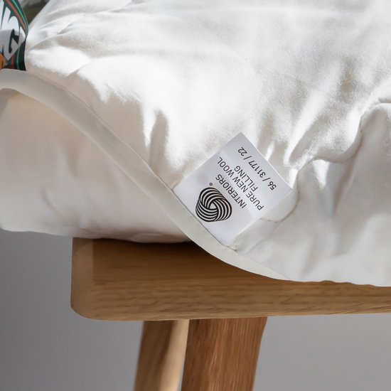 Detail van een wit wollen dekbed met label 'PURE NEW WOOL FILLING'.