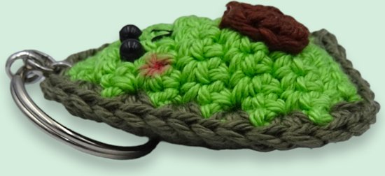 Gehaakte avocado sleutelhanger met ogen, mondje en steen.