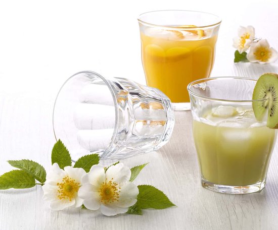 Verres Duralex Picardie avec des boissons. Un verre avec une boisson verte et du kiwi, un avec une boisson orange et des tranches d'orange. Deux fleurs blanches.