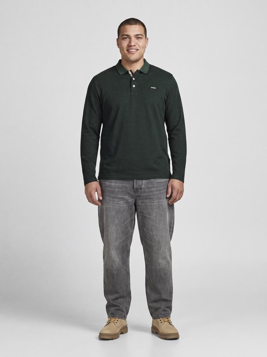 Model draagt een donkergroen poloshirt met lange mouwen, grijze jeans en beige schoenen.