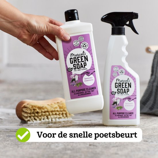 Hand met Marcel's Green Soap allesreiniger spray met lavendel en rozemarijn, naast een borstel.