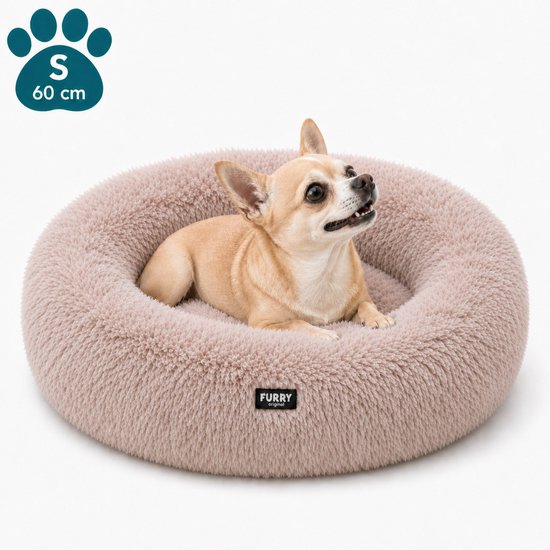 Een klein bruin hondje ligt in een zacht, rond, roze hondenmand van Furry Original.