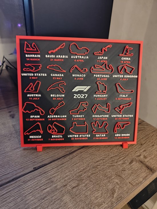 Plaque murale avec représentation 3D du calendrier des courses F1 2027 en noir et rouge, avec noms de pays et dates.