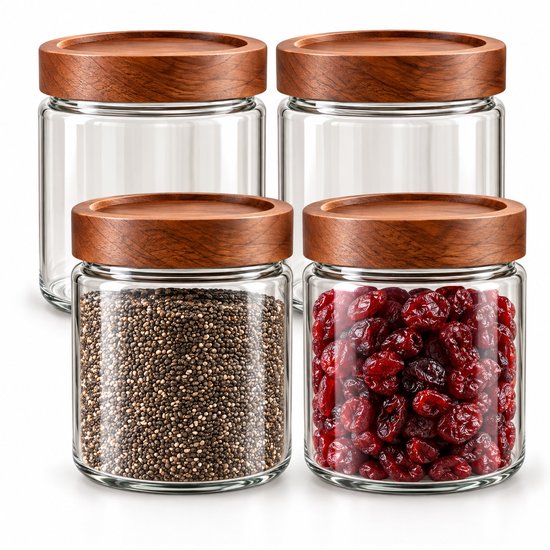 Quatre bocaux en verre vides avec couvercles en acacia, deux remplis de graines de chia et de canneberges.