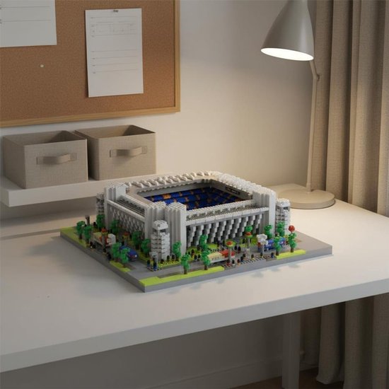 Bouwset van het Bernabéu Stadion met witte constructie, blauwe tribunes en een groen veld op een bureau.